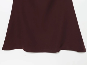 Detailed macro view of the wine red evening gown hem with precise stitching and fabric texture