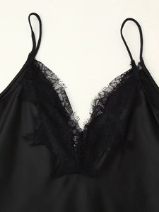 Detail der zarten Wimpernspitze am schwarzen Satin-Ausschnitt des Slip-Kleides