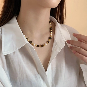 Collier vintage perles oeil de tigre et nacre porté par un mannequin sur chemise blanche