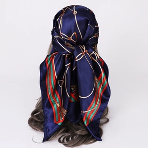 Detail of navy blue silk square scarf with red green stripes and gold chain print on hair