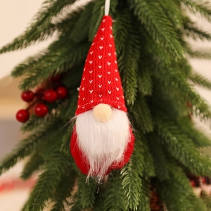 Close-up of knitted Christmas gnome ornament with white beard hanging on festive tree