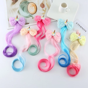 Flat lay of colorful unicorn hair clips with long wavy wigs and glittery bows for girls