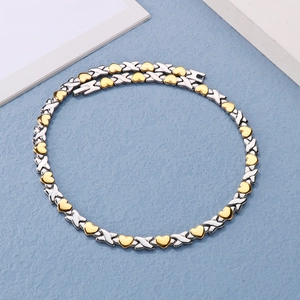 Detail of bicolor necklace with silver X-links and gold heart links on blue background