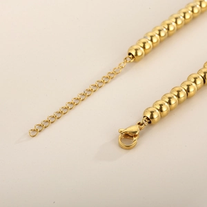 Detailed macro shot of the golden lobster clasp and extender chain on a ball chain necklace