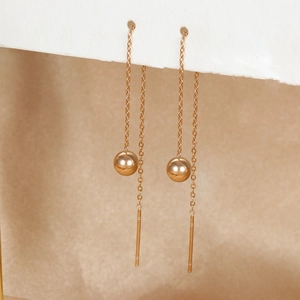 Detailed view of long gold drop earrings with polished beads and sleek tassel chains