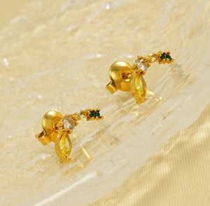 Vue macro d'un piercing banane en acier 18K serti de pierres jaunes et vertes