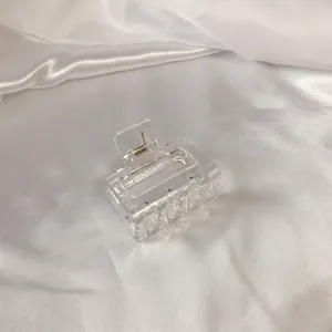 Macro shot of minimalist transparent rectangular hair claw clip on white silk fabric