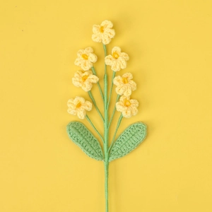 Detailed view of hand-knitted yellow wool forget-me-not flowers with green stems