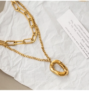 Close-up of double-layer gold geometric chain necklace with irregular oval pendant