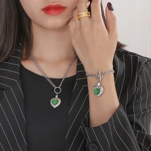 Parure élégante collier et bracelet cœur argenté avec pierres vertes portés par le mannequin