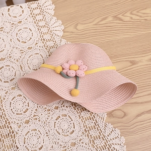 Gros plan d'un chapeau de paille rose pour enfants avec fleurs et pompons
