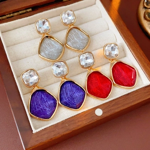 Gros plan de boucles d'oreilles vintage en or avec pierres géométriques en gris, violet et rouge