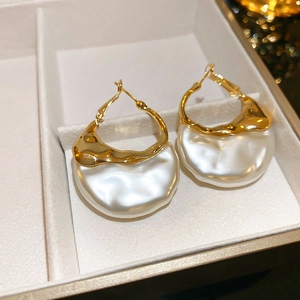 Detail of gold metal hook earrings with irregular white pearls in a jewelry box