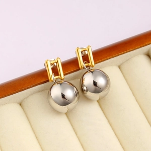 Minimalist gold and silver two-tone geometric drop earrings in a jewelry box