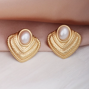 Détail macro de boucles d'oreilles vintage dorées avec perle blanche sur fond en soie