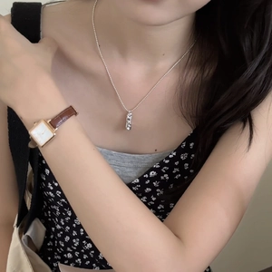 Elegant silver textured pendant necklace paired with a vintage brown leather watch