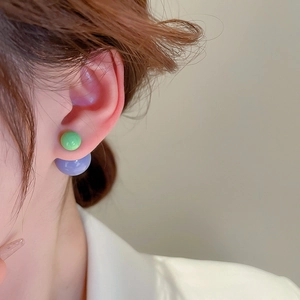 Detailed view of dual-color round ball earrings in lime green and light purple hues