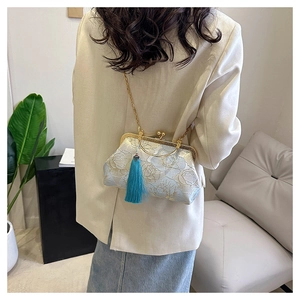 Detailed view of blue floral embroidery handbag with metal chain and green tassel