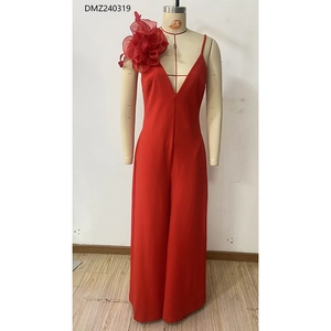 Détail d'une combinaison rouge à col en V profond avec une grande fleur 3D à l'épaule