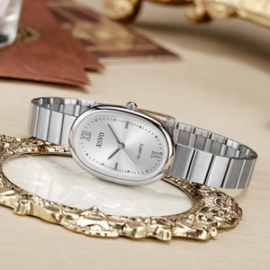 Detail of elegant silver oval quartz watch displayed on a decorative gold frame