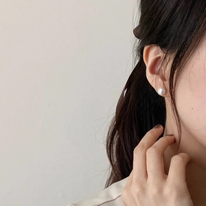 Close-up detail of a minimalist 925 sterling silver stud earring with a white round pearl