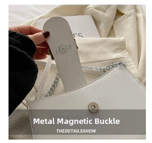 Detail of silver magnetic closure and chain strap on minimalist white crossbody bag