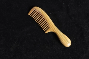Close-up of a natural sandalwood comb with thick rounded handle and wide teeth detail