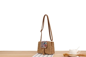 Gros plan du sac bohème en paille tressée avec perles colorées et pompons
