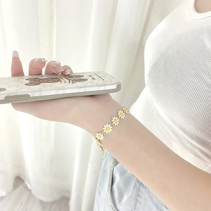 Elegant daisy chain bracelet with white enamel petals on a golden metal base