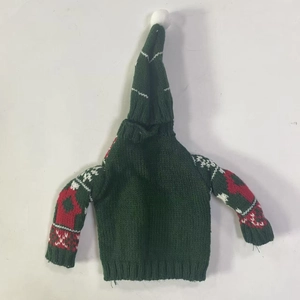 Detail of green knitted Christmas wine bottle cover with red jacquard patterns and pom-pom