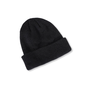 Detailed close-up of thick black knit beanie featuring classic minimalist ribbed texture