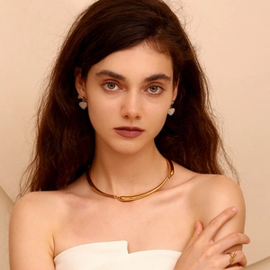 Close-up of elegant gold collar necklace and sparkling heart-shaped earrings on a model