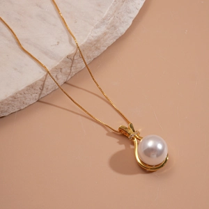 Elegant gold necklace with white pearl pendant and tiny diamonds on pink background