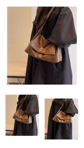 Detail of a brown leather shoulder bag featuring a flap closure and gold chain strap