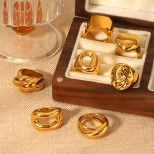 Chunky gold stainless steel rings in geometric and heart shapes on a jewelry display