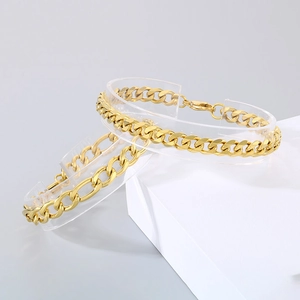 Macro detail of gold Cuban link and Figaro chain bracelets on geometric stands