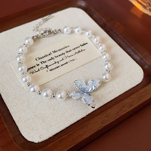 Gros plan d'un bracelet en perles et papillon avec cristaux bleus sur un plateau en bois