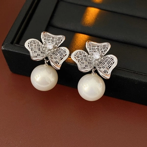 Detailed view of silver flower earrings with zircon centers and large white pearls
