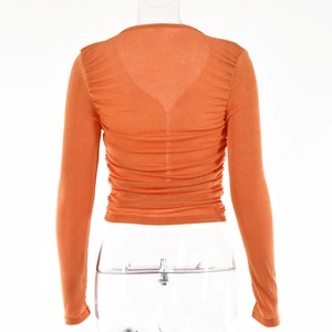 Détail du haut orange à manches longues avec dos froncé et design en V à coupe ajustée