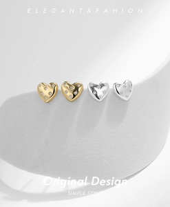 Macro shot of gold and silver heart stud earrings with sparkling zircon inlay