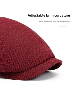 Detail of dark red knit newsboy cap featuring wide curved brim and textured weave pattern