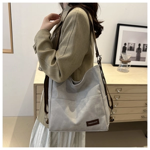Close-up of a large grey canvas tote bag worn by a model in a minimalist room