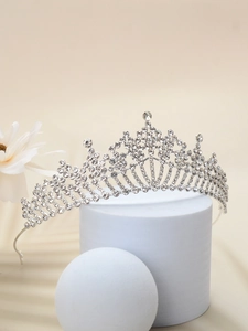 Elegant silver bridal crown with sparkling rhinestones on a white geometric stand