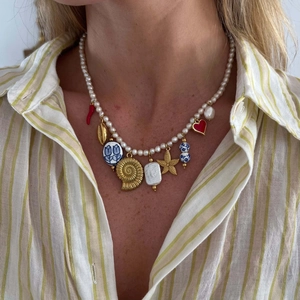 Close-up of pearl necklace with gold shell starfish and heart pendants on model