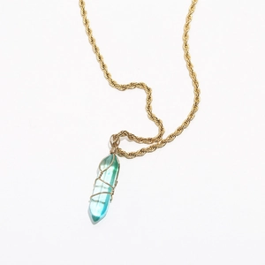 Detail of turquoise crystal pendant with golden twist chain on white background