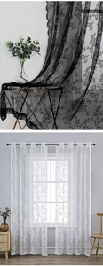 Detailed view of black and white lace curtains with elegant floral patterns and wavy edges