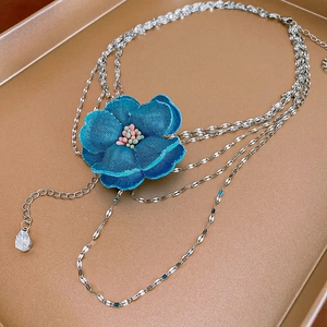 Détail macro du pendentif fleur en tissu bleu et collier multi-rangs vintage chic