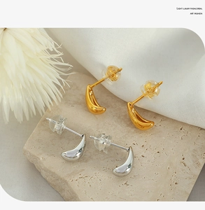 Detailed view of teardrop earrings in gold and silver finish on stone base