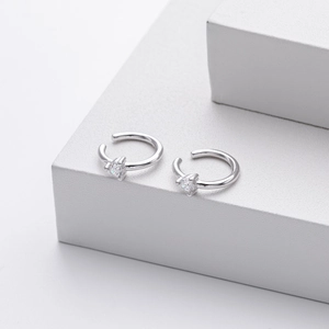 Detail shot of silver S925 C-shape ear cuffs with sparkling heart zircon on white stand