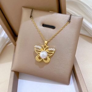 Detail of gold butterfly necklace with zircon wings and pearl center in a gift box